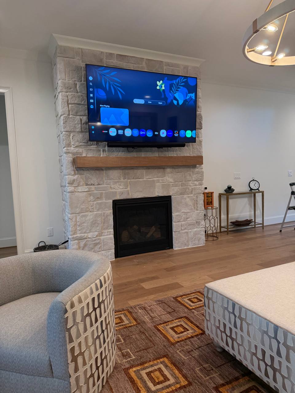 75-inch LG TV on motorized pull-down mount with Sonos soundbar above stone fireplace in Roxboro NC